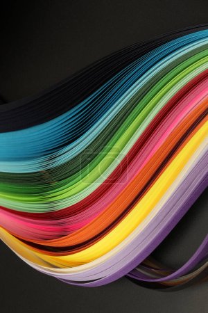 Foto de Arco iris multicolor de neón tira de papel ondulado. Textura abstracta fondo negro. - Imagen libre de derechos