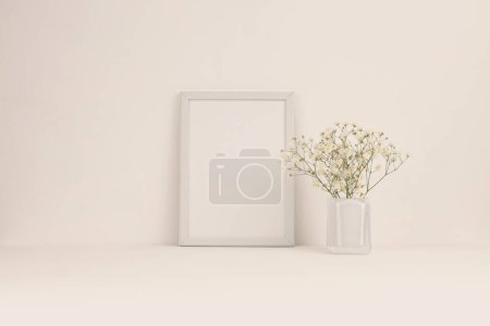 Téléchargez les photos : Table de bureau (étagère) avec cadre vide et fleurs. Espace de copie créatif Ligt beige espace de travail neutre. - en image libre de droit