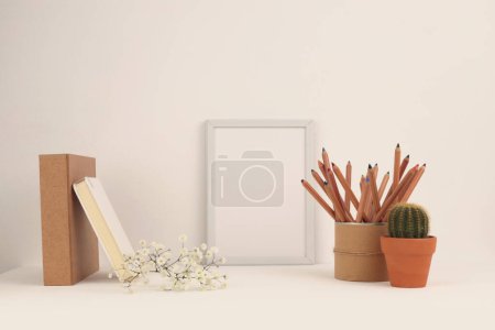 Foto de Mesa de oficina (estante) con marco vacío y objetos decorativos. Copiar espacio creativo Ligt beige espacio de trabajo. - Imagen libre de derechos