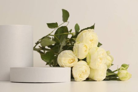 Téléchargez les photos : Bouquet de fleurs de rose jaune sur le podium blanc. Fond beige clair. Scène de présentation minimale du produit d'affichage vide. - en image libre de droit
