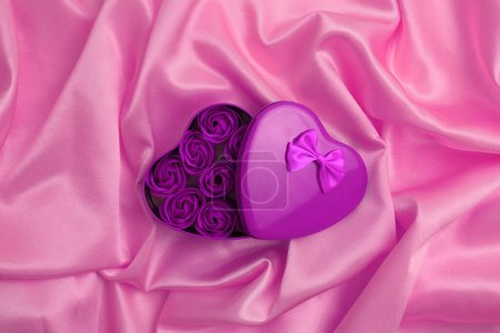 Foto de Caja regalo marco corazón con flores de color rosa. Abstracto violeta rosa perla onda seda textura fondo. - Imagen libre de derechos
