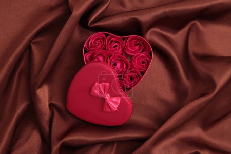Foto de Caja regalo marco corazón con flores de color rosa. Abstracto marrón perla onda seda tela textura fondo. - Imagen libre de derechos