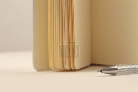 Foto de Libro abierto, bloc de notas y pluma sobre fondo horizontal neutro beige. - Imagen libre de derechos