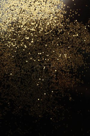 Foto de Oro (bronce) brillo puntos confeti brillo en negro. Luz abstracta parpadeo brillo fondo vertical. - Imagen libre de derechos