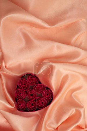 Foto de Caja regalo marco corazón con flores de color rosa. Abstracto Beige rosa perla onda seda tela textura fondo. - Imagen libre de derechos