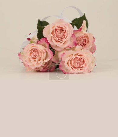 Foto de Ramo de flores rosa con cinta de seda. Luz beige copia espacio fondo. - Imagen libre de derechos