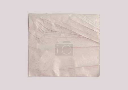 Foto de Pieza de papel de nácar de textura desmenuzada desgarrada vacía sobre fondo de pared beige neutro. - Imagen libre de derechos