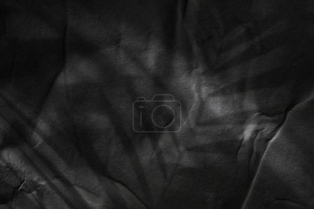 Foto de Papel húmedo arrugado negro textura en blanco espacio de copia luz y sombra fondo pared de piedra. - Imagen libre de derechos