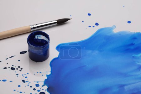 Photo for Paintbrush and ink blue color drop blot on paper background. - Royalty Free Image