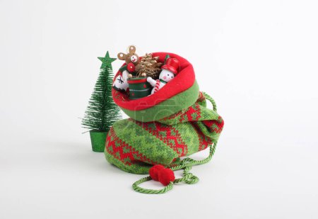 Foto de Bolso de punto de Navidad con pequeños juguetes de regalo de Navidad decorativos. - Imagen libre de derechos