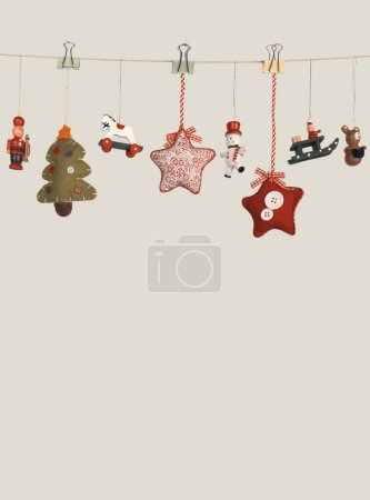Foto de Pequeño juguete decorativo de Navidad de madera colgar guirnalda en la pared gris beige. - Imagen libre de derechos