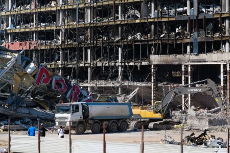Foto de UCRANIA, KYIV, 25 DE MARZO DE 2022: Un misil ruso destruyó el centro comercial y de entretenimiento Retroville el 20 de marzo. Excavadora limpiando escombros. Después del bombardeo. Terror y genocidio del pueblo ucraniano - Imagen libre de derechos