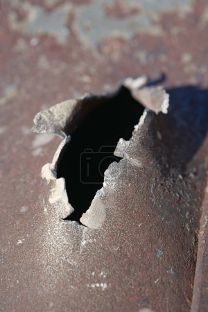Foto de Hole in metal from a real missile explosion. After bombing. War in Ukraine, terror and genocide of Ukrainian people. Russian missile destroyed houses and metallic garages in residential area - Imagen libre de derechos
