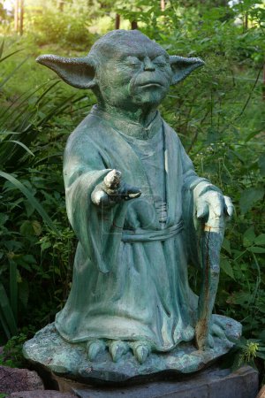 Foto de KYIV, UCRANIA, 16 DE JULIO DE 2022: Escultura del Maestro Yoda - personaje ficticio de La Guerra de las Galaxias, que medita con los ojos cerrados, se encuentra en el jardín botánico central de Kiev. Que la fuerza esté contigo. - Imagen libre de derechos