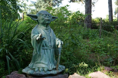 Foto de KYIV, UCRANIA, 16 DE JULIO DE 2022: Escultura del Maestro Yoda - personaje ficticio de La Guerra de las Galaxias, que medita con los ojos cerrados, se encuentra en el jardín botánico central de Kiev. Que la fuerza esté contigo. - Imagen libre de derechos