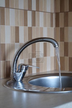 Photo for From the tap is flows water. Water pours in a strong stream from the tap in kitchen - Royalty Free Image