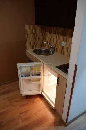 Téléchargez les photos : Mini réfrigérateur vide intégré avec porte ouverte dans la cuisine - en image libre de droit
