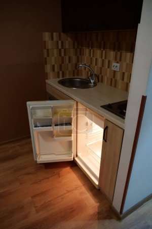 Téléchargez les photos : Mini réfrigérateur vide intégré avec porte ouverte dans la cuisine - en image libre de droit