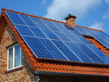 Panneaux solaires au sommet des maisons résidentielles avec un ciel bleu clair, illustrant l'adoption par les ménages des avantages de l'énergie propre et de l'énergie solaire.