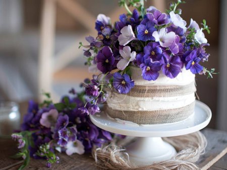 Photo for An eco conscious wedding cake featuring vegan, gluten free layers, organic flowers, and a burlap ribbon. - Royalty Free Image