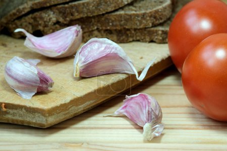 Photo for A cutting board topped with sliced tomatoes and garlic. - Royalty Free Image