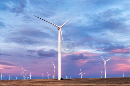 Photo for The sun sets on the Wyoming Wind turbines giving the clouds a beautiful colorful sky across the wind farm - Royalty Free Image