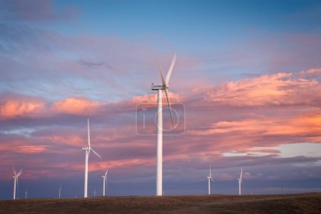 Photo for The sun sets on the Wyoming Wind turbines giving the clouds a beautiful colorful sky - Royalty Free Image
