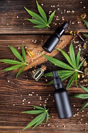 Téléchargez les photos : Bouteille d'huile de cannabis, feuilles de chanvre cbd et cannabis sur table en bois. vue de dessus. - en image libre de droit