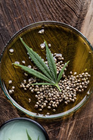 Téléchargez les photos : Huile de cannabis et graines de marijuana sur une table en bois sombre - en image libre de droit
