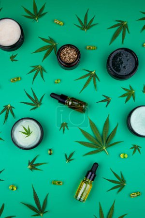 Foto de Aceite de cáñamo, marihuana, hojas de cáñamo, aceite sobre fondo verde. plano, vista superior. - Imagen libre de derechos