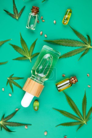 Téléchargez les photos : Huile de cannabis en bouteille avec pipette et feuilles de cannabis avec cannabis sur fond de papier rose - en image libre de droit