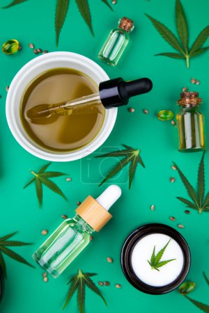 Foto de Aceite de cáñamo, marihuana, hojas de cáñamo, botella de aceite y pipeta, sobre un fondo verde. Vista superior, acostado. plano laico, - Imagen libre de derechos
