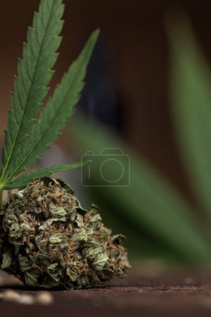 Téléchargez les photos : Marijuana leaves with buds and cannabis on the background of dark wooden table - en image libre de droit