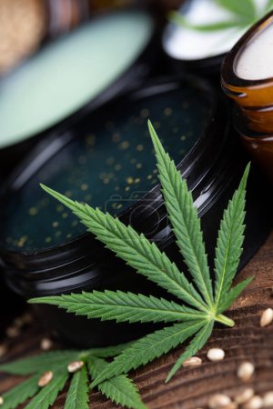 Téléchargez les photos : Huile de cannabis cbd dans un bol avec feuille sur fond de table - en image libre de droit