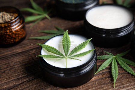 Téléchargez les photos : Huile de cannabis dans un pot en verre avec des feuilles de chanvre sur fond noir. - en image libre de droit
