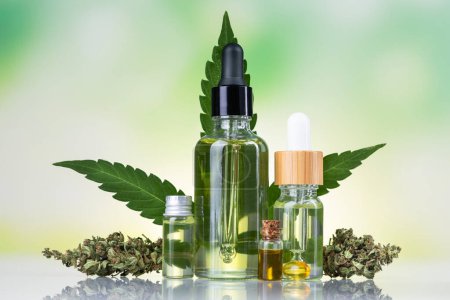 Téléchargez les photos : Huile de cannabis dans des pots en verre et bouteille avec des feuilles de chanvre sur fond blanc - en image libre de droit