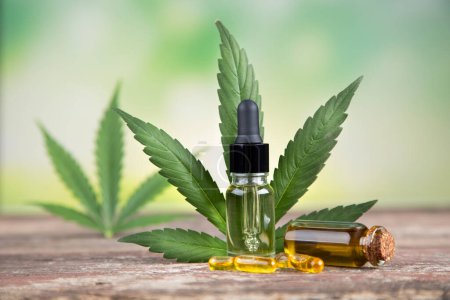 Téléchargez les photos : Huile de cannabis en bouteille avec feuille de chanvre vert frais sur surface en bois - en image libre de droit
