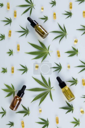 Photo for Bottles of essential oil and cannabis leaves with hemp oil on a white background. top view - Royalty Free Image