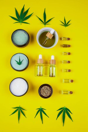 Foto de Cannabis, aceite de cbd y productos de cannabis, hojas de cáñamo y una botella con aceite de cáñamo sobre un fondo verde. Vista superior. plano laico. - Imagen libre de derechos