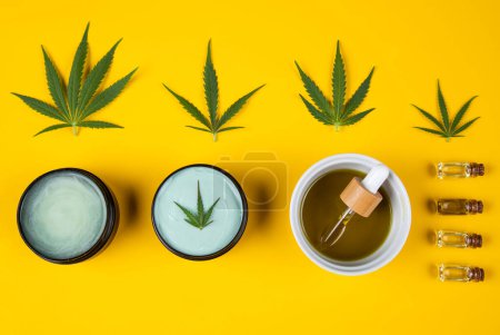 Photo for Top view of hemp oil in bowl with cannabis and marijuana leaf on yellow background with copy space - Royalty Free Image