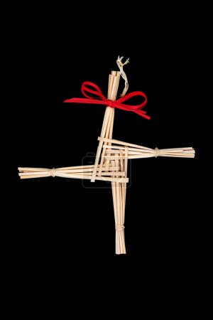 Foto de Saint Brigids Cross pagan symbol of house blessing protection from evil and fire. Traditionally made in Ireland on Imbolc St Brigids feast day. On black, top view. - Imagen libre de derechos