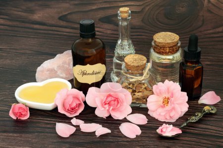 Photo for Aphrodisiac concoction for magic love potion spell. Saw palmetto herb, rose flowers ,honey, oil, spring water and concoction in a bottle with rose quartz crystal. Valentines Day concept. - Royalty Free Image