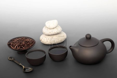Photo for Japanese kuchika tea ceremony for balance with pebble stack, ceramic tea set. Zen spiritual mindfulness harmony concept on gradient grey. Healthy asian culture drink. - Royalty Free Image