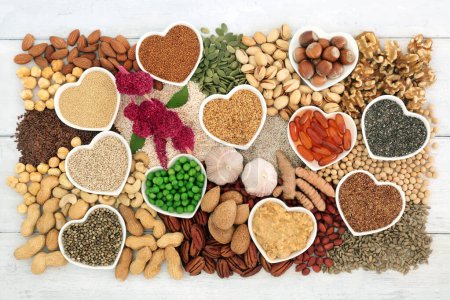 Vegan healthy heart food high in lipids essential fatty acids containing unsaturated good fats for low cholesterol levels with nuts, seeds, vitamin e capsules, vegetables and grain.
