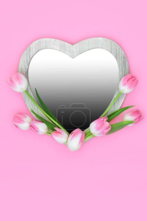 Foto de Hermoso marco en forma de corazón de flor de tulipán con inserto de gradiente sobre fondo rosa. Primavera floral mínima, Día de las Madres, Aniversario y diseño de la naturaleza de Pascua. - Imagen libre de derechos