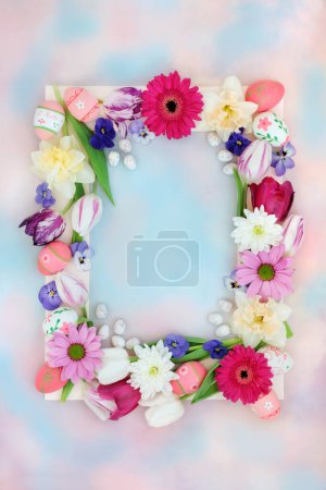Decorative Easter background border with eggs, flowers on pastel blue pink sky cloud background. Natural nature frame design for the holiday and Spring season.