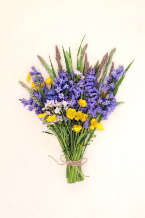 Spring bluebell, buttercup, nemesia flower bouquet with meadow grasses on hemp paper. Floral British Beltane wildflower and meadow flowers nature composition. 