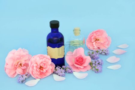 Ätherisches Öl mit Rosen- und Lavendelblüten und rosa Blüten auf blauem Grund. Natürliche florale Heilmedizin zur Behandlung von Hauterkrankungen, Schlaflosigkeit, Angstzuständen, fördert die Entspannung.