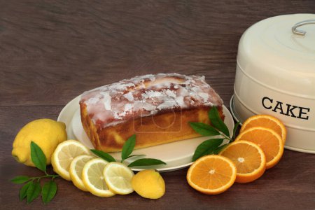 Zitronen- und Orangennieselkuchen mit frischem Obst und Blättern und Kuchenform auf rustikalem Holzgrund. Hausgemachtes Dessert zum Nachmittagstee.