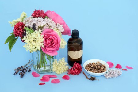 Healing adaptogen flowers and herbs with valerian root, rose, elder and lavender flowers used in natural herbal medicine. Medicinal sedative food ingredients with tincture bottle on blue.